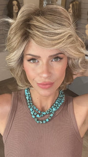 Madeline wearing MONROE by BELLETRESS in BUTTERCAKE BLONDE-R | A neutral-warm blonde blend featuring light brown, ash, and lightest blonde tones with natural-looking darker roots for added depth and realism.