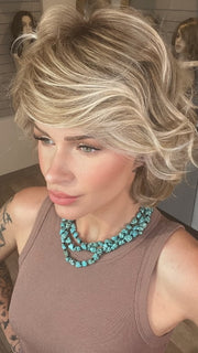 Madeline wearing MONROE by BELLETRESS in BUTTERCAKE BLONDE-R | A neutral-warm blonde blend featuring light brown, ash, and lightest blonde tones with natural-looking darker roots for added depth and realism.