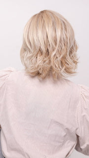 Roxie wearing ALICANTE by BELLETRESS in CRUSHED ALMOND BLONDE R | A soft Neutral Light Blonde with a Light and Medium Blended Root Color.