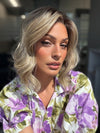 Roxie is wearing VERONICA by BELLETRESS in SPARKLING CHAMPAGNE BLONDE R | A radiant blend of champagne blonde with soft golden and beige tones, grounded by natural-looking roots in ash brown and dark blonde.
