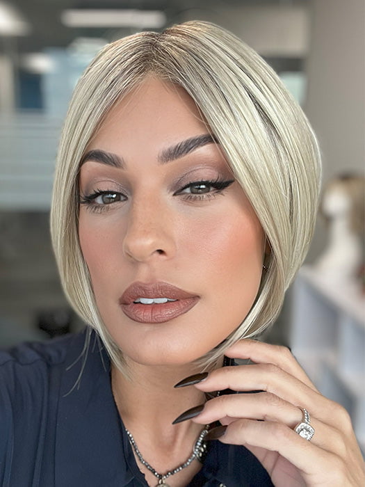 Model is wearing AYUMI by NORIKO in color Light Ash Blond R | Cream Ash Blonde with ash brown and white-grey roots that blend into a variety of ash blonde tones, including ash pearl blonde, creamy ivory, and pale cream