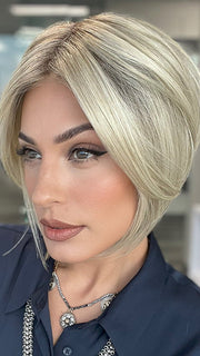 Model is wearing AYUMI by NORIKO in color Light Ash Blond R | Cream Ash Blonde with ash brown and white-grey roots that blend into a variety of ash blonde tones, including ash pearl blonde, creamy ivory, and pale cream