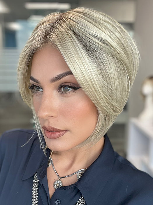 Model is wearing AYUMI by NORIKO in color Light Ash Blond R | Cream Ash Blonde with ash brown and white-grey roots that blend into a variety of ash blonde tones, including ash pearl blonde, creamy ivory, and pale cream
