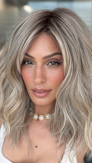 Model is wearing BEACH WAVE MAGIC by TRESSALLURE in color 36/25/23/R6 MOON DUST | Dark salt and pepper base with blended golden blonde and cool platinum tones, shaded with Dark Roots