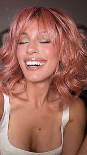 Model is wearing BREEZY WAVEZ by RENE OF PARIS in color DUSTY-ROSE | Medium Coral Red Base with Dark Brown Roots