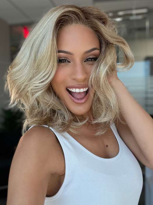 Roxie is wearing AMANDA by ENVY in color CHAMPAGNE SHADOW | Soft Dark Blonde with Platinum Highlights and Chestnut Roots