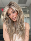Model is wearing California Beach Waves by TressAllure in color 10/27/88/R6 ALMOND CREAM | Dark roots transition into a beautiful blend of light brown, pale auburn, and platinum tones.