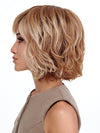 Model is wearing FLAWLESS WAVES by TRESSALLURE in color EL12/22/8 | Light Golden Brown Evenly Blended with Platinum Blonde Highlights with Medium Brown Roots