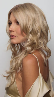 Model is wearing HANA by NORIKO in color Light Ash Blond R | Cream Ash Blonde with ash brown and white-grey roots that blend into a variety of ash blonde tones, including ash pearl blonde, creamy ivory, and pale cream