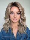 Sandy @i_be_wiggin wearing KELLY by BELLE TRESS in color BUTTERCAKE BLONDE-R | A neutral-warm blonde blend featuring light brown, ash, and lightest blonde tones with natural-looking darker roots for added depth and realism.