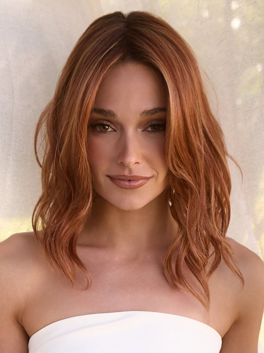 Model is wearing MAUDE by Amore in color RUSTY-SUNRISE-R | Dark brown roots transition into a deep auburn tone with light copper blonde highlights for depth and dimension.