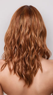 Model is wearing MAUDE by Amore in color RUSTY-SUNRISE-R | Dark brown roots transition into a deep auburn tone with light copper blonde highlights for depth and dimension.