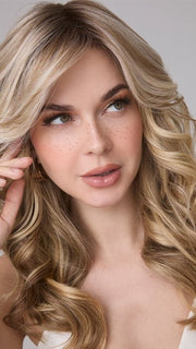 Model is wearing MEDIUM WAVY TP MONO by AMORE in color SEA SALT BLOND R | A perfect mixture of cool, icy-blond and warm-dark blond. The rich brown root tone enhances the modern appearance. 
