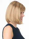 Model is wearing PAIGE PETITE by ENVY in color SPARKLING CHAMPAGNE | Medium Brown roots with overall Strawberry Blonde base and soft Golden Blonde highlights