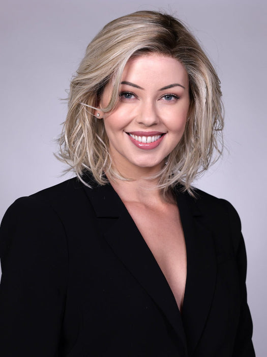 Model is wearing PARK AVE By BELLETRESS in CRUSHED-ALMOND-BLONDE-R | A Soft Neutral Light Blonde with a Light and Medium Blended Root Color