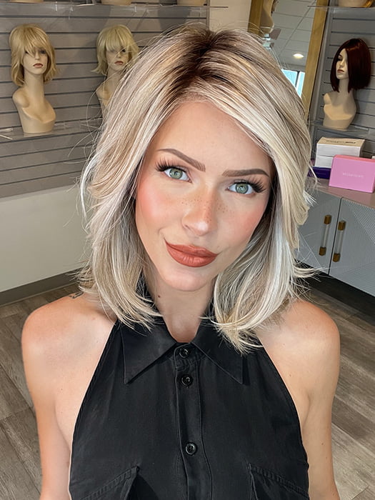 Madeline wearing PARK AVE by BELLE TRESS in color MILKSHAKE BLONDE R | A mixture of Light Sandy Brown, Highlighted with Light Ash Blonde with a Hint of Light Platinum Blonde with a Medium Root Color