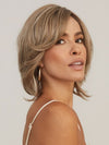 Model is wearing SHEENA by RENE OF PARIS in color CHAMPAGNE SUNSET | Dark/medium multi-tonal blond with textured honey, ash, and golden hues and chocolate brown roots