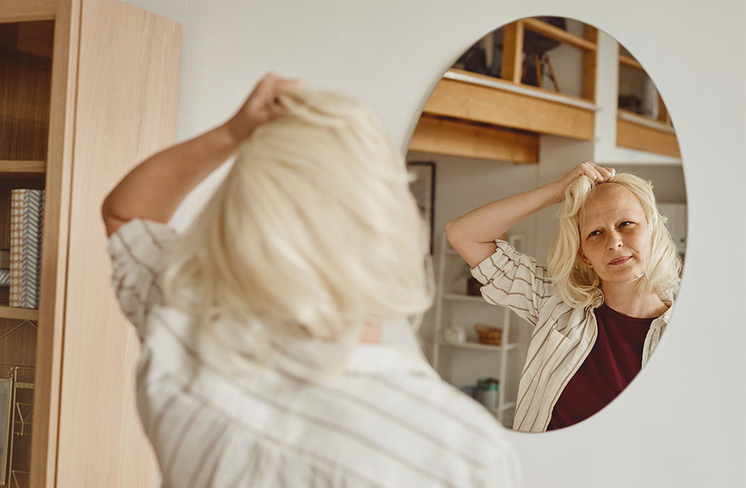 Woman staring at the mirror with wig