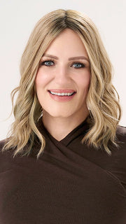 Model is wearing BARELY THERE WAVY 12" TOPPER in color PROSECCO | BROWN ROOTS WITH GOLDISH BLONDE HIGHLIGHTS