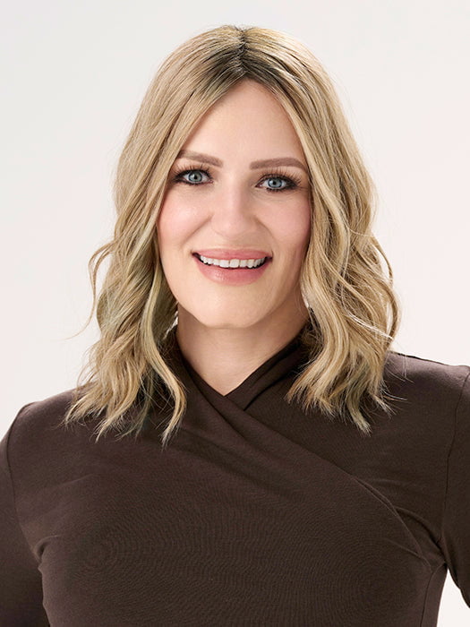 Model is wearing BARELY THERE WAVY 12" TOPPER in color PROSECCO | BROWN ROOTS WITH GOLDISH BLONDE HIGHLIGHTS