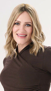 Model is wearing BARELY THERE WAVY 12" TOPPER in color PROSECCO | BROWN ROOTS WITH GOLDISH BLONDE HIGHLIGHTS