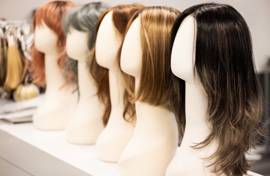 Row of different colored wigs on wig stands
