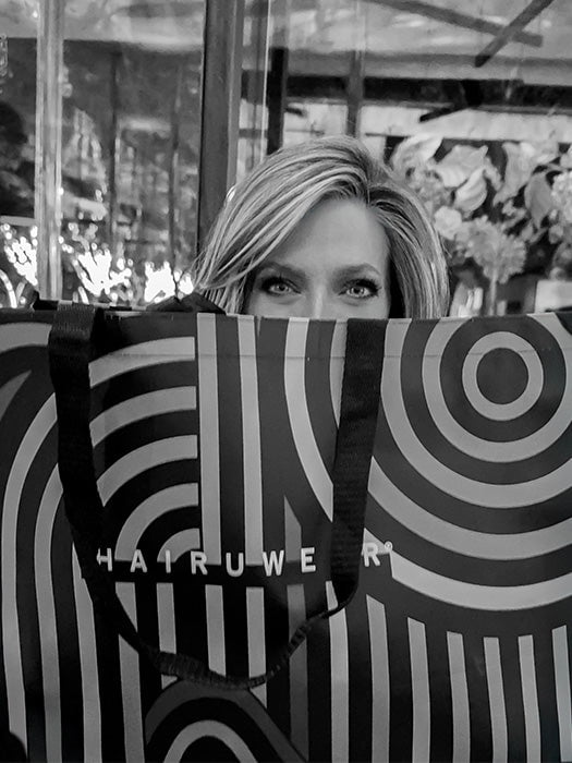 Wigs.com Ambassador Kristyna Moore peers over her swag bag from Raquel Welch