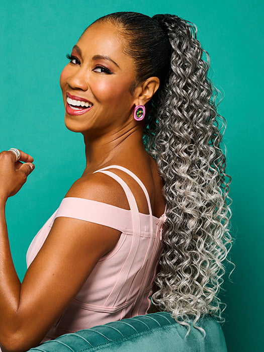Model is wearing 27" GLAM CURLS PONY by KIM KIMBLE in color MC511SS POWDERED LICORICE | Dark Grey with Light Grey Highlights