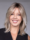 Model is wearing MONACO by BELLETRESS in color MILKSHAKE BLONDE R | A mixture of Light Sandy Brown, Highlighted with Light Ash Blonde with a Hint of Light Platinum Blonde with a Medium Root Color