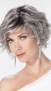 Model is wearing ROMANCE DELUXE by ELLEN WILLE in color METALLIC GREY ROOTED 60.51 | Pearl White, Darkest/Lightest Brown with Grey Blend with Shaded Roots