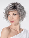 Model is wearing ROMANCE DELUXE by ELLEN WILLE in color METALLIC GREY ROOTED 60.51 | Pearl White, Darkest/Lightest Brown with Grey Blend with Shaded Roots